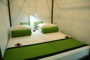 米瑞莎斯拉小屋酒店的一张位于带两个绿色和白色枕头的房间的床位