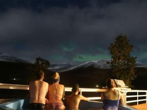 达尔维克Höfði Cottages的一群人坐在浴缸里,看着北极光