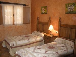 Zarza la Mayor康普勒霍佩尼亚菲耶尔酒店的一间卧室设有两张床和一张桌子上的台灯。