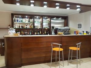 菲夏诺Hotel Santa Caterina的酒吧设有2把凳子和瓶装酒精饮品