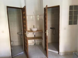 姆布尔Guesthouse Dalal ak Jàmm的浴室配有盥洗盆和带镜子的淋浴