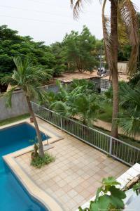 瓦加杜古B & B Le Nomade的棕榈树游泳池旁的围栏