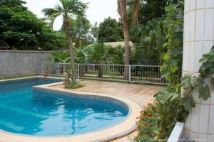 瓦加杜古B & B Le Nomade的一个带围栏和棕榈树的庭院内的游泳池