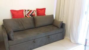 萨尔瓦多Studio Lateral vista mar Barra cama de casal Netflix的上面有两个红色枕头的沙发