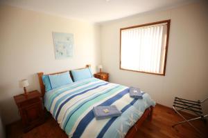 Stokes Bay袋鼠岛海浪野生小屋的一间卧室配有蓝色和白色床单