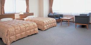 伊东伊藤园酒店的酒店客房带两张床和一张桌子以及椅子。
