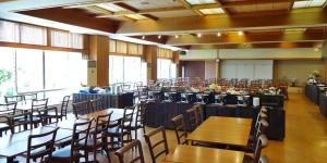 伊东伊藤园酒店的宴会厅配有桌椅和窗户