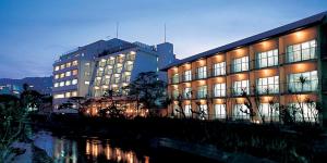 伊东伊藤园酒店的一座大型建筑,在河边设有灯光窗户