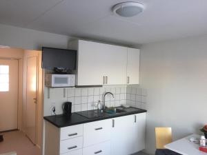 伊德勒Fjällstuga的厨房配有白色橱柜、水槽和微波炉