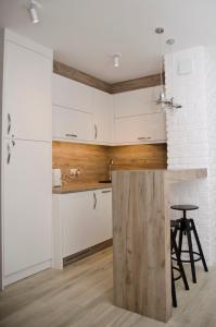 奥尔什丁kameralny apartament的厨房配有白色橱柜和带凳子的台面