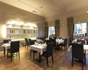 布拉格安盟酒店的用餐室配有白色桌子和黑色椅子