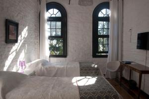 亚特兰蒂斯达Santoral Restaurante y Posada Pet Friendly的一间卧室配有一张床、一张书桌和两个窗户。