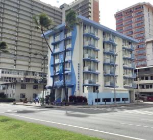 檀香山Holiday Surf Hotel (with full kitchen)的街道前方有棕榈树的建筑