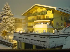 巴德小基希海姆Landhaus Krenn的一座黄色的大建筑,有雪,还有一棵圣诞树