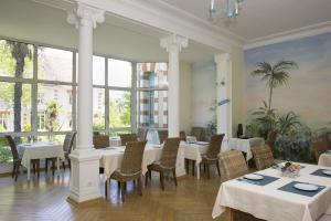 阿卡雄Résidence de Tourisme Vacances Bleues Villa Regina的餐厅设有白色的桌椅和大窗户。