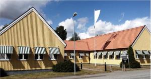 韦斯特罗斯Hotell Hässlö的黄色建筑,有红色屋顶和白色旗帜
