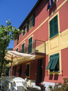 佐阿利Affittacamere Cerisola 2003的粉红色的建筑,设有阳台、遮阳伞和椅子