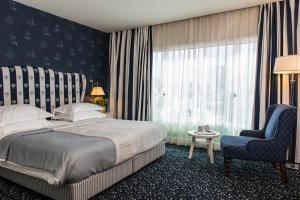 特拉维夫沙洛姆酒店 - 阿特拉斯精品酒店的卧室配有床、椅子和窗户。