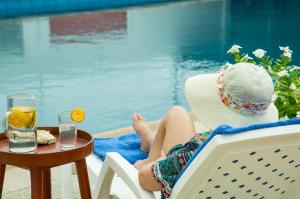 通苏帕Hotel RC Tonsupa的坐在游泳池边椅子上的戴帽子的女人