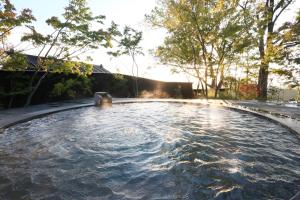 南小国町黑川温泉御所月光树日式旅馆的一座树木繁茂的庭院内的游泳池