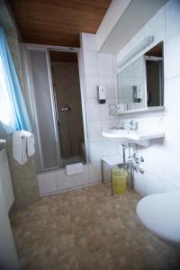 阿罗萨Hotel Hold AG的带淋浴、盥洗盆和镜子的浴室