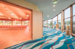 瓦伦Kurzentrum Waren (Müritz)的大房间设有色彩缤纷的地毯和窗户