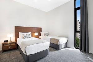 墨尔本Melbourne CBD Central Apartment Hotel Official的酒店客房设有两张床和窗户。