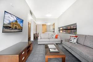 墨尔本Melbourne CBD Central Apartment Hotel Official的客厅配有沙发和桌子