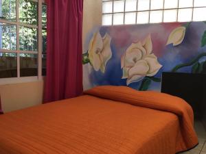 希利特拉Hotel Jovita的一间卧室配有一张橙色床,墙上挂有绘画作品