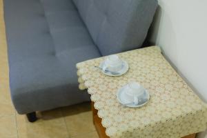 芭东海滩Rabbit Mansion Patong - SHA Plus的一张桌子,上面有两个杯子和碟子,放在沙发边