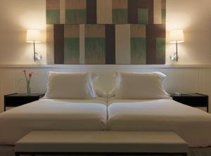 圣蓬萨H10卡萨德尔玛尔酒店的一张带两个枕头和两个灯的大白色床