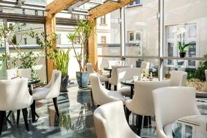 科沃布热格Jantar Hotel & SPA by Zdrojowa的餐厅设有白色的椅子和桌子以及窗户。