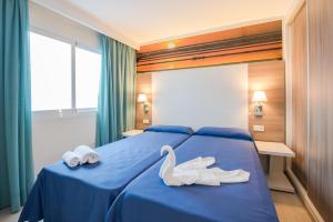 圣安东尼奥洛杉矶公寓式酒店的两个天鹅坐在蓝色的床边