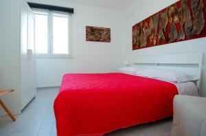 拉斯卡里Villa Pasquale...immersa nella tranquillita'的白色的窗户客房内的一张红色的床