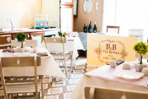 圣塞韦罗B&B Via Roma的一间设有白色桌椅的餐厅,标有bc葡萄酒酒窖的标志