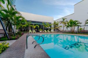 莱蒂西亚怀拉套房酒店的棕榈树建筑前的游泳池