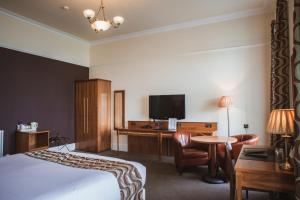 安斯特拉瑟白可酒店的酒店客房配有一张床、一张书桌和一台电视。