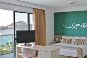 维多利亚Praia do Canto Apart Hotel的酒店客房配有一张床和一张带电脑的书桌