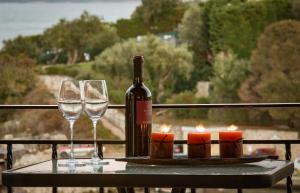 卡西奥皮Villa Perris Studios的一瓶葡萄酒和两张带蜡烛的桌子上的玻璃杯