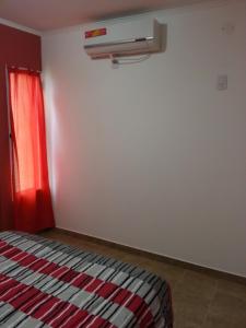 圣何塞Bungalows Don Heraldo的一间卧室配有一张带红色窗帘和加热器的床