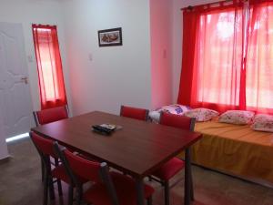 圣何塞Bungalows Don Heraldo的一间设有桌子和一张带红色窗帘的床的房间