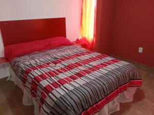 圣何塞Bungalows Don Heraldo的一间卧室配有一张带红色床头板的床和窗户