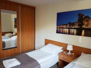 格但斯克琥珀假日酒店的一间卧室设有两张床,墙上挂着一幅大画