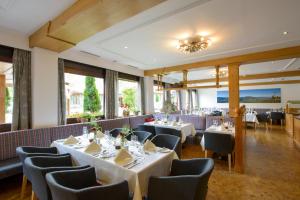 伦格里斯阿拉贝拉布劳内克酒店的餐厅设有白色的桌椅和窗户。