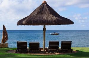 普拉亚多提沃利爱克雷索特普拉亚酒店的海洋里三把椅子和一把带船伞