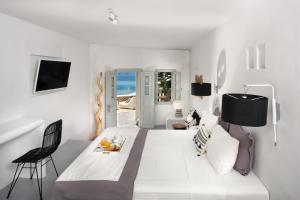 AgaliBlue Sand Boutique Hotel & Suites的白色卧室配有一张大床和椅子