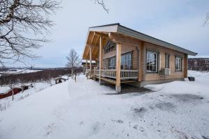 NuorgamArctic Aurora Borealis cottages的雪地小木屋,有雪覆盖的地面