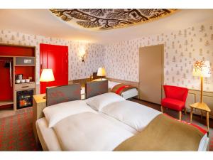 苏黎世瑞士之夜法斯宾德酒店的酒店客房,设有两张床和一张红色椅子