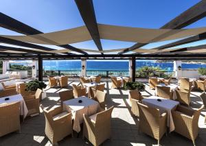 圣特雷莎加卢拉COLONNA GRAND HOTEL CAPO TESTA, a Colonna Luxury Beach Hotel, Santa Teresa Sardegna的一个带桌椅的庭院和大海