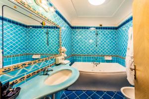 伊斯基亚亚拉贡宫温泉酒店的蓝色瓷砖浴室设有浴缸和水槽